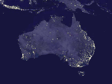 The satellite images shows Australia from above at night. The distribution of light spots is denser along the east coast with very light areas corresponding to the coastal location of the major metropolitan centres, including the south and southwest. Smaller bright spots occur in the north and the centre of the country.